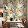 Floral Spring Vibes wildflower wallpaper in coral, yellow, blue and lavender on a dining nook wall with a wooden table and orange chairs