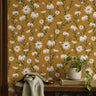 wallpaper with white daisies on a golden yellow background behind entryway shelf
