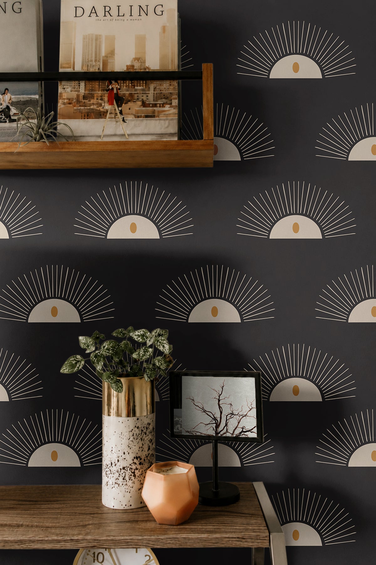 Boho Sunburst 204 black geometric wallpaper with cream sunburst motifs and warm gold accents styled above a modern wood console