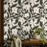 ivory floral wallpaper with dark olive leaves behind a wood shelf with potted plant