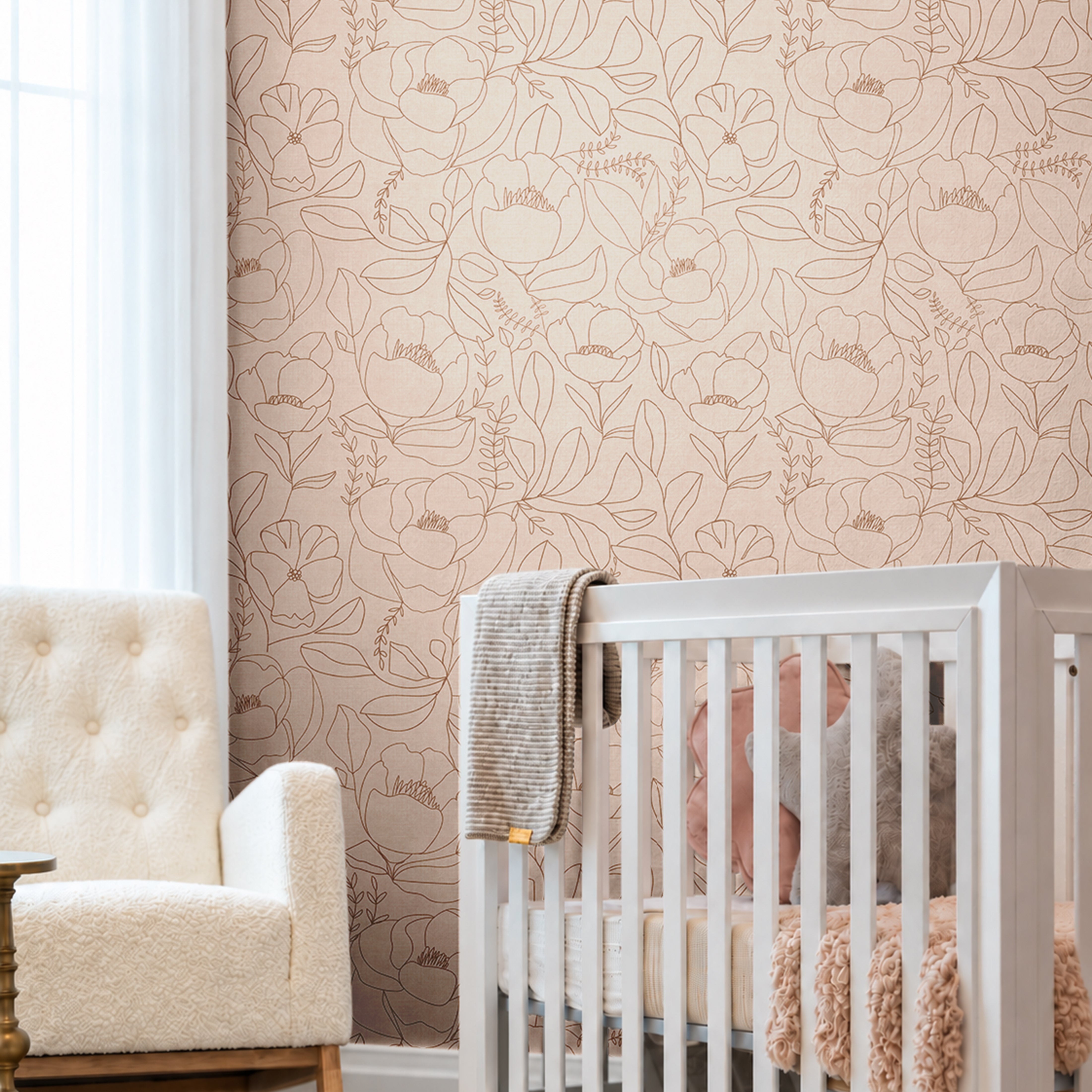 Open Bloom blush floral wallpaper in a neutral nursery with delicate brown line art flowers, white crib and upholstered