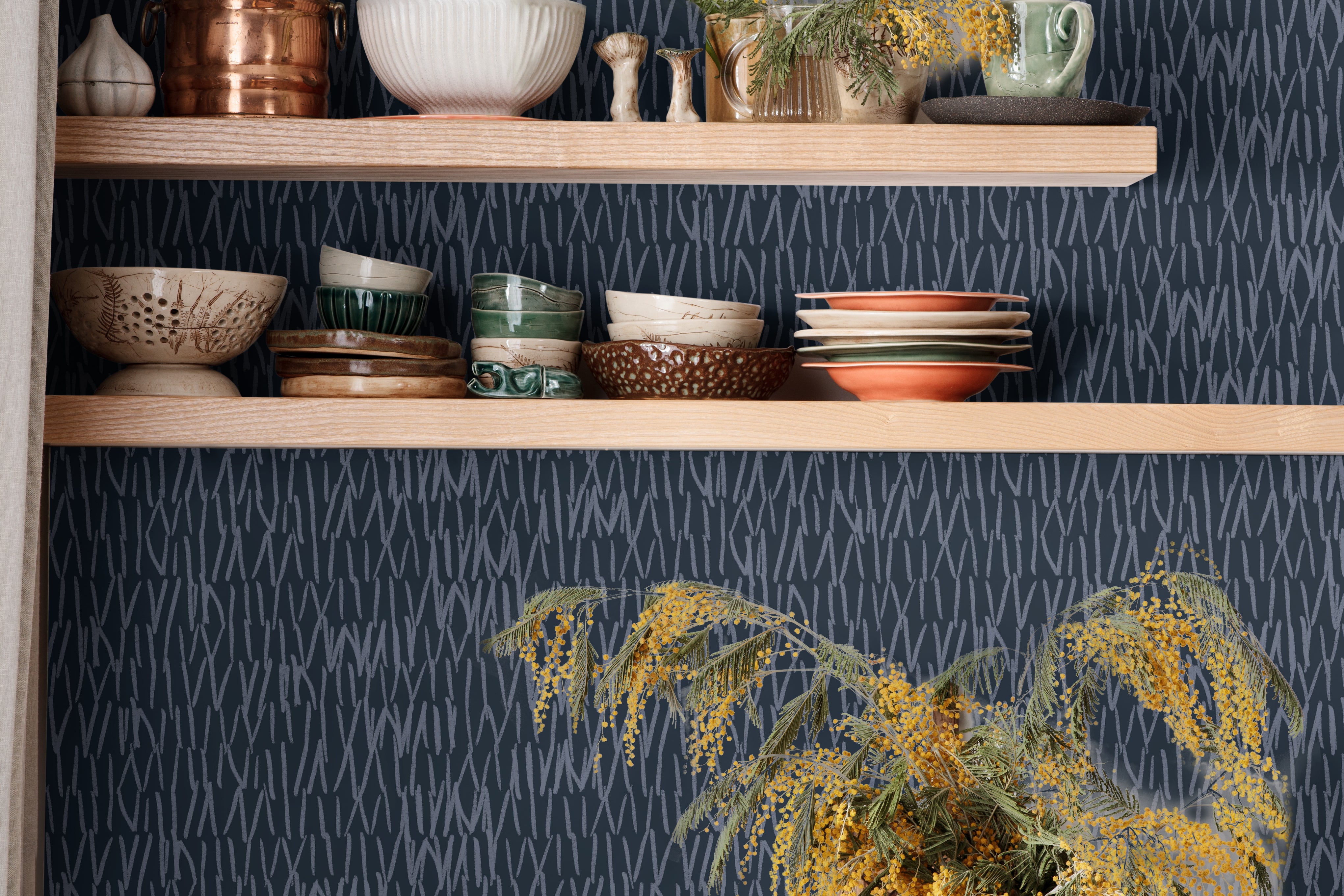 navy abstract line wallpaper behind open wood kitchen shelves with blue dishes black faucet and white
counter