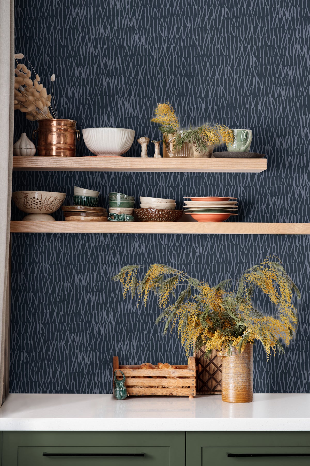 navy abstract line wallpaper behind open wood kitchen shelves with blue dishes black faucet and white
counter