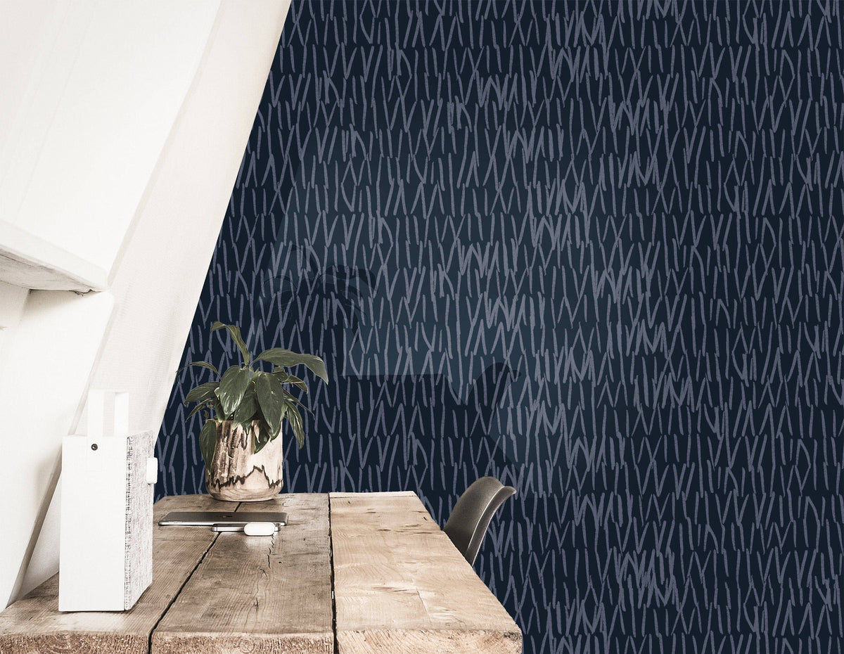 navy abstract line wallpaper behind a rustic wood desk with a potted plant, document holder, and dark chair under a sloped ceiling