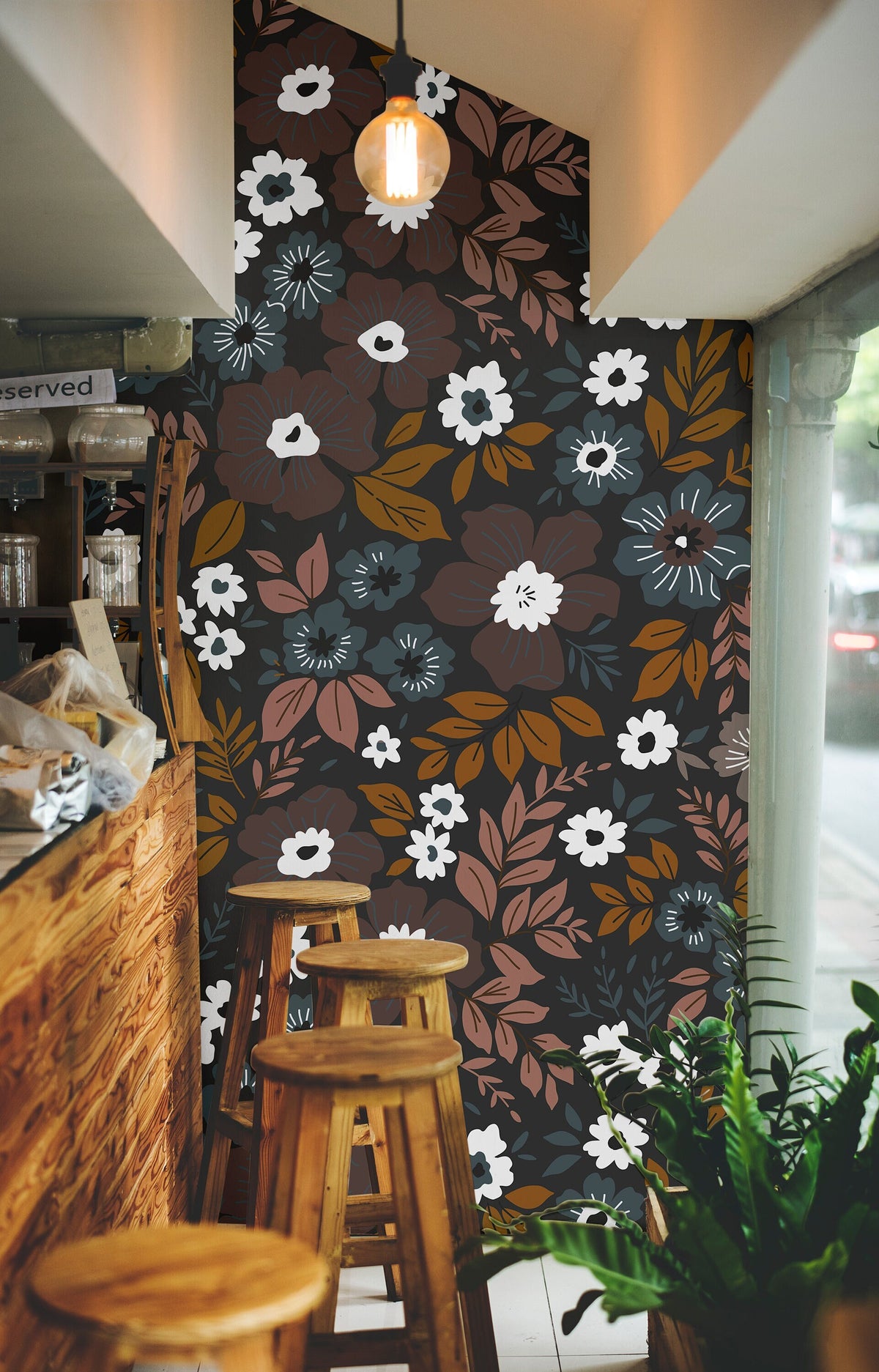 Wallpaper 1060a: Retro floral wallpaper with white, amber, rust, and dusty blue flowers against a dark background in a cozy café interior.